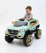 Un jeune garçon souriant au volant de son nouveau 4x4 électrique enfant style BMW vert avec des jantes jaunes.