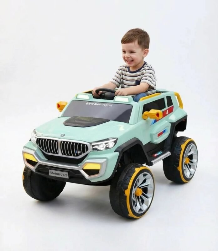 Un jeune garçon souriant au volant de son nouveau 4x4 électrique enfant style BMW vert avec des jantes jaunes.